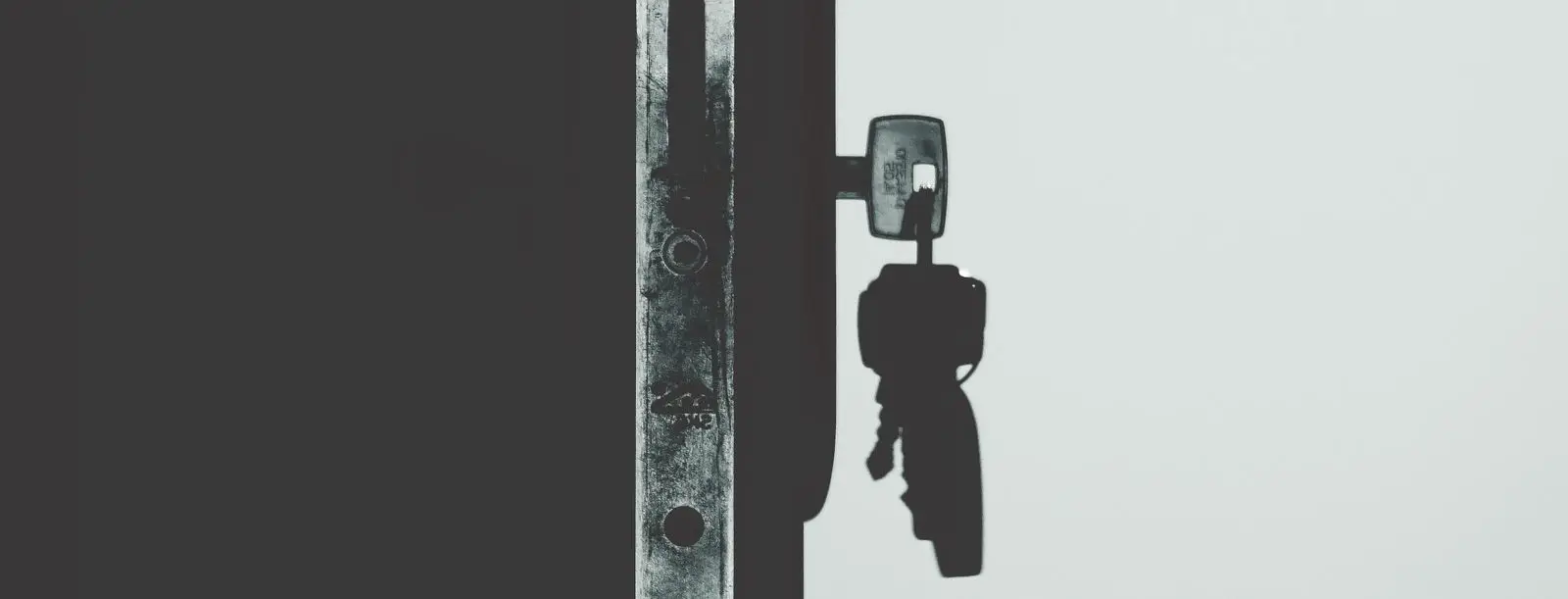 Llave en una cerradura que proyecta su sombra, en blanco y negro