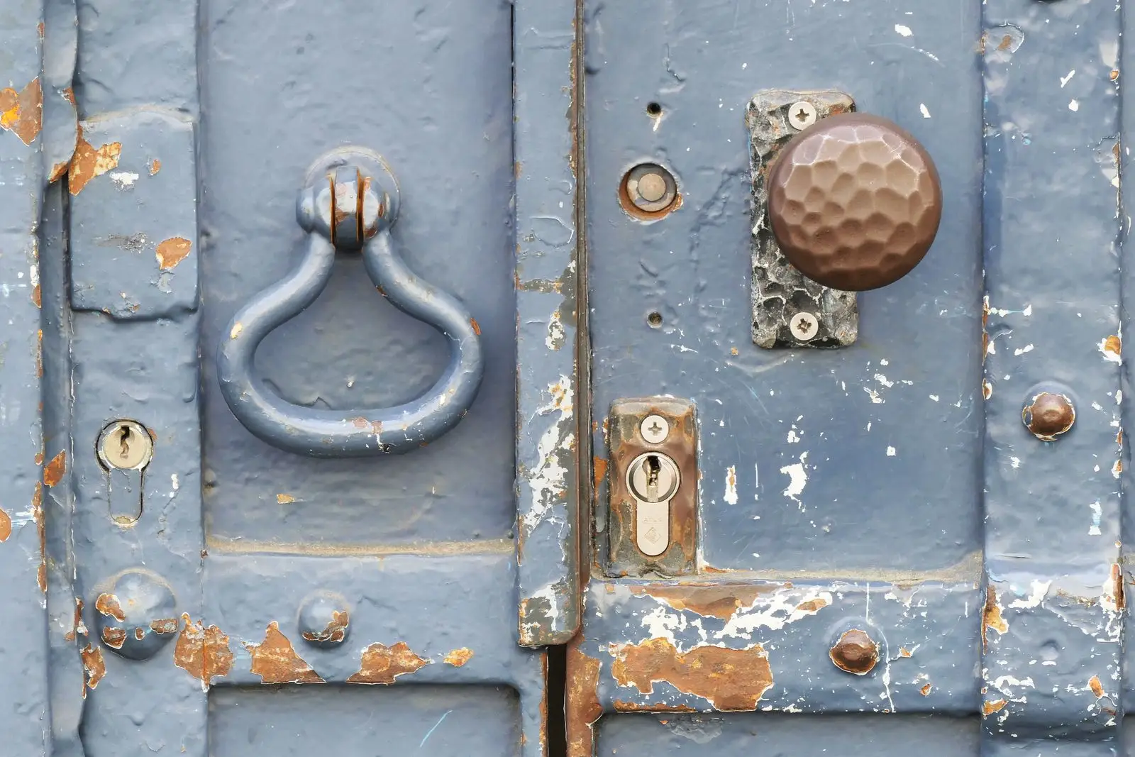 Puerta azul desgastada con una cerradura antigua y un pomo
