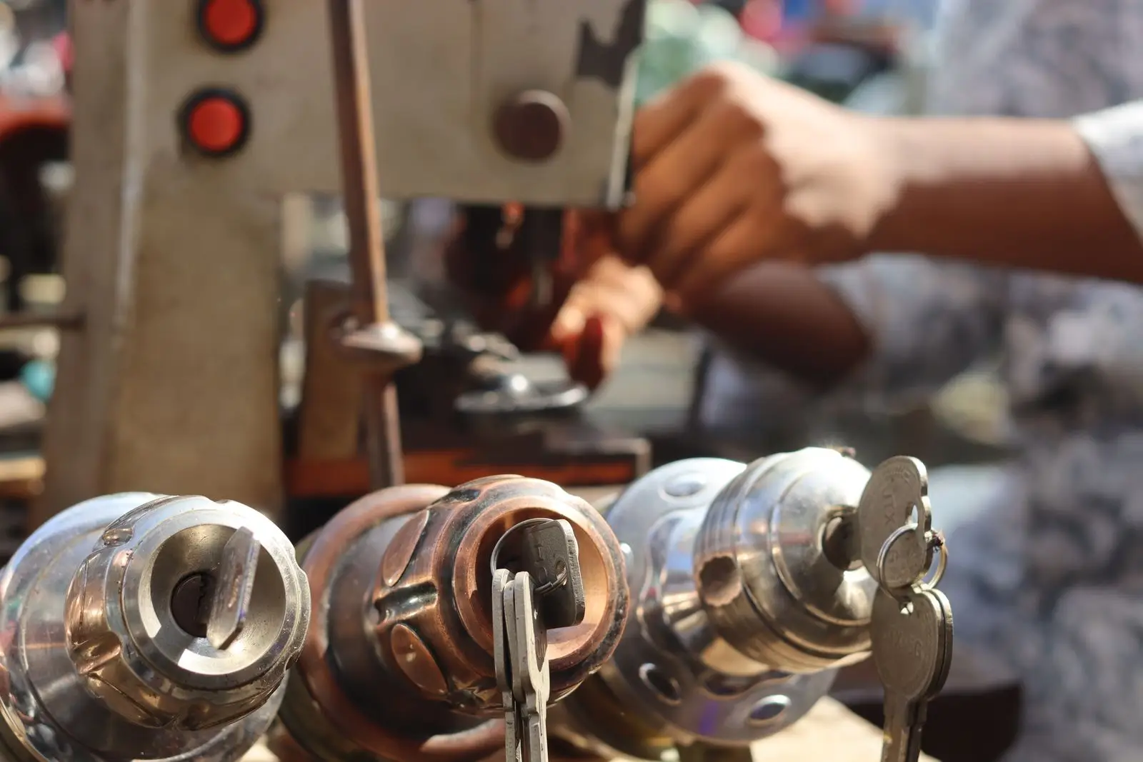 Manos trabajando con una máquina de copiar llaves, con varios cilindros y llaves en primer plano
